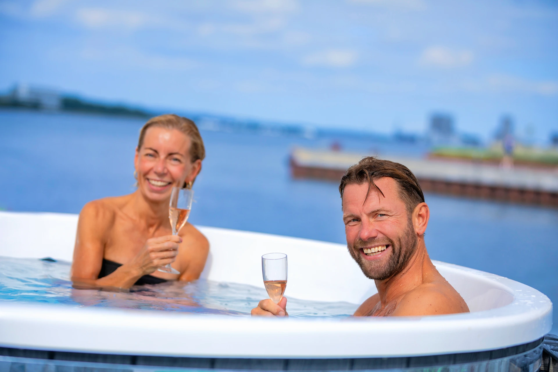 mand og kvinde smiler til kameraet fra en hottub